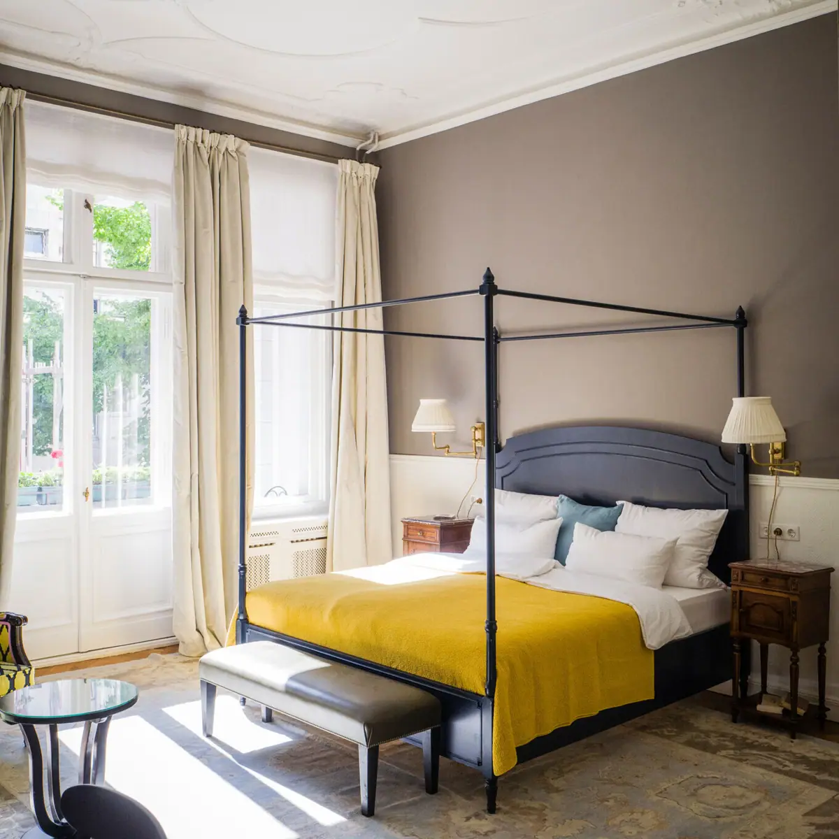 A Salon room at the HENRI Hotel Berlin with a bed and large windows.