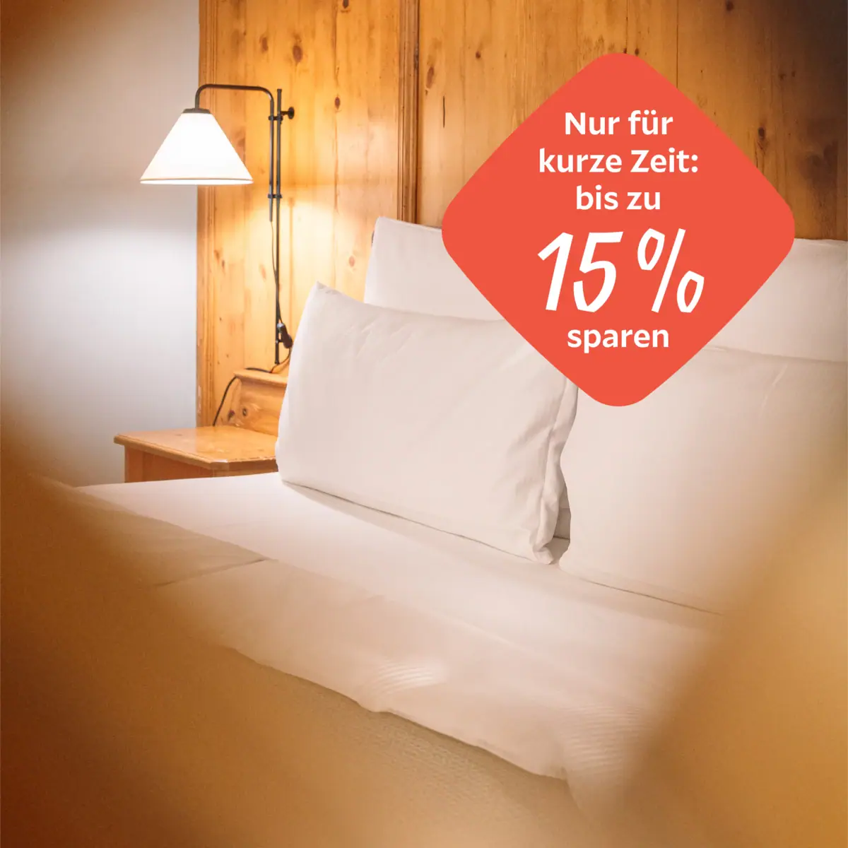 A bed with white sheets and a lamp.