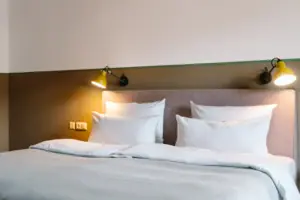 A bed with white cushions and a lamp.