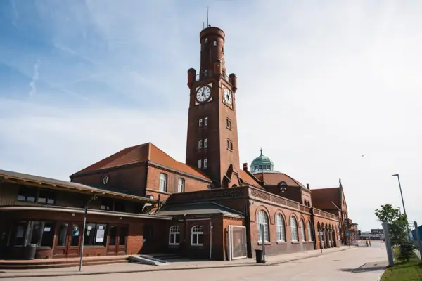 The Hapag-Hallen in Cuxhaven, a brick building with a clock tower, under a cloudy sky.