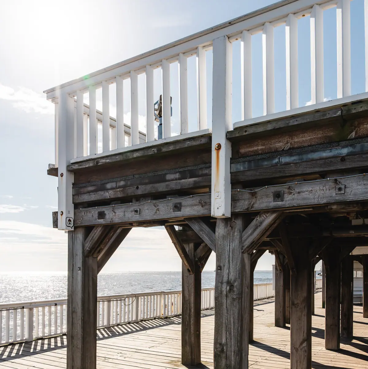 A wooden deck with white railings on a sunny day