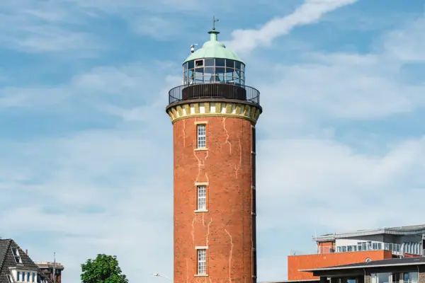 The Hamburg Lighthouse in Cuxhaven, with its green roof and a building in the background.
